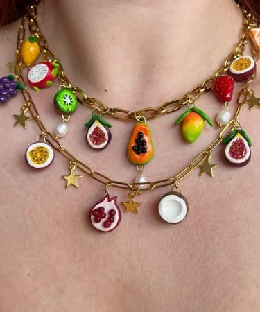 Dos collares colocados en el cuello, con charms en forma de frutas