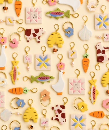 Charms de distintas formas, colores y tamaños sobre un fondo beige.