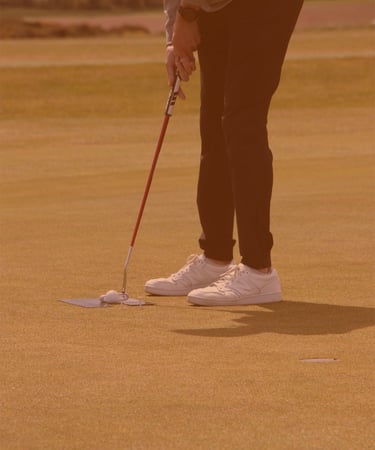 A golfer setting up for a putt on the green, focusing on their stroke, with a serene golf course setting in Aberdeen