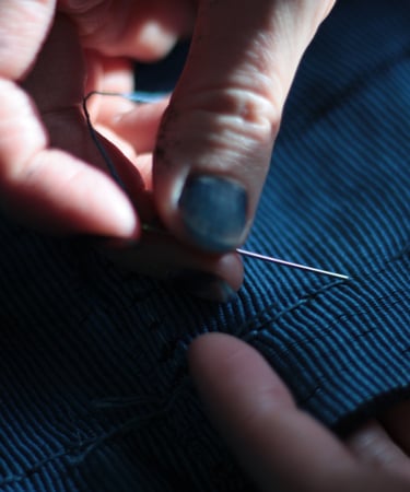 artist sewing her own textiles dyed in her indigo vat