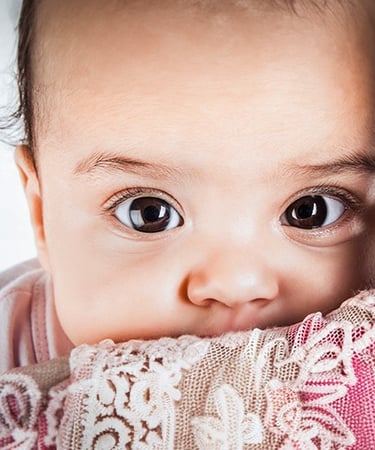 a baby girl with a pink blanket on her lap