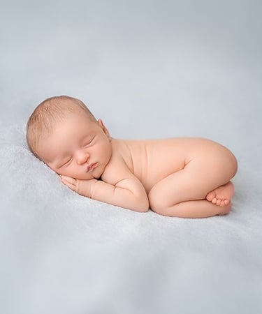 a baby sleeping on a blanket in a studio
