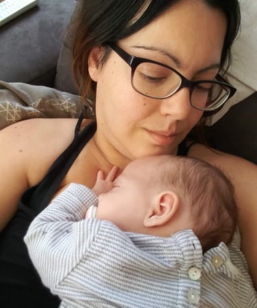 a woman in glasses and a black top hat is holding a baby