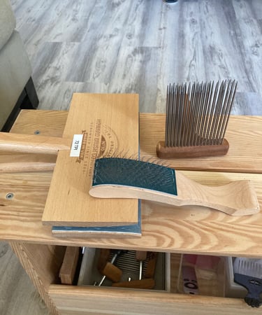 Wool carders and a comb on a wooden bench