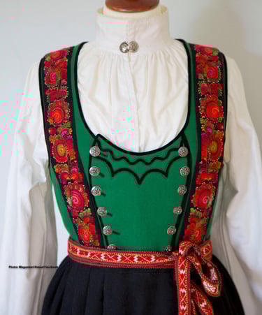 A green bodice bunad with rose embroidery on a mannequin