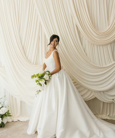 a woman in a white wedding dress standing in front of a curtain