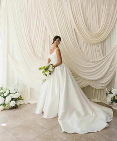 a woman in a white wedding dress standing in front of a curtain