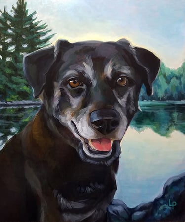 A black dog with graying fur around her eyes and muzzle sits before a mountain lake.