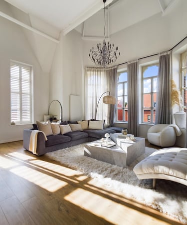 Modernes luxuriöses Wohnzimmer mit grauem Ecksofa, Marmorcouchtisch und grossen, bogenförmigen Fenst