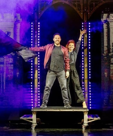 Professional magicians performing a live stage magic show with purple smoke and theatrical lighting.