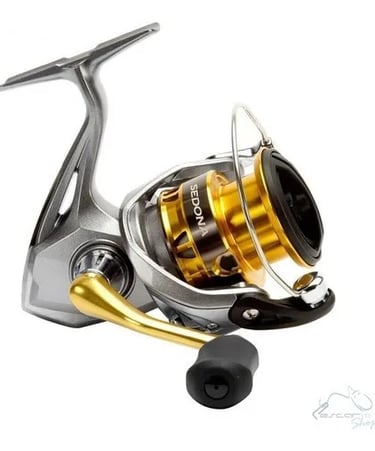 molinete shimano para pesca tucunaré prata com detalhes dourado letras branca posição invertida.