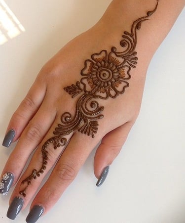 a woman's hand with henna tattoo of a flower design
