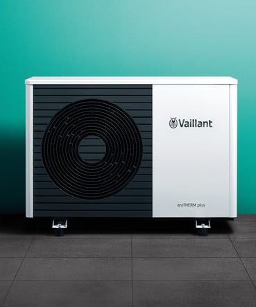 a white and black heat pump with a green wall