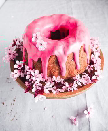 babka z malinowym lukrem udekorowana kwiatami wiśni