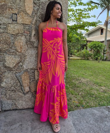 Mulher em pé usando um vestido com babado franzido, estampado nas cores rosa e laranja