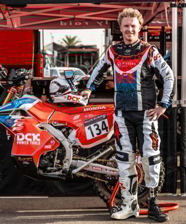 Professional rally racer with a prosthetic leg standing next to his Honda dirt bike at Rallye du Maroc.