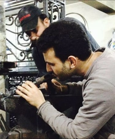 Un ferronnier artisan est en train de façonner une pièce métallique.