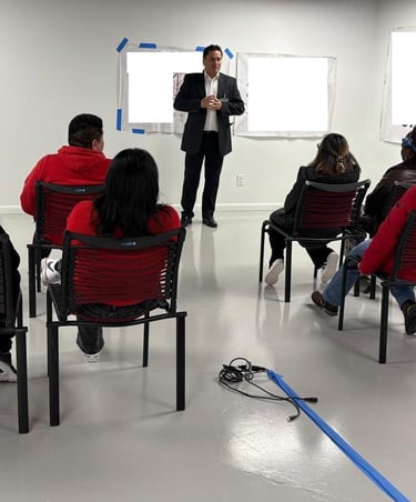 Professional business seminar with a speaker presenting to a diverse group of seated workshop participants.