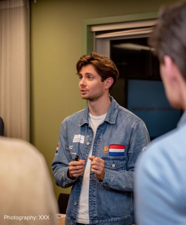 A young professional man in a denim jacket leading a workshop discussion during a business seminar.