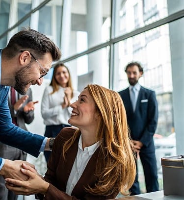 Un hombre y una mujer felices de verse y se aprietan las manos.