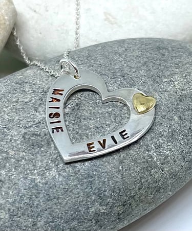 A silver heart necklace personalised with 2 names on either side and a 24ct gold heart accent