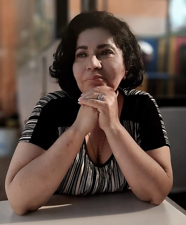 a woman sitting at a table with her hands on her chin