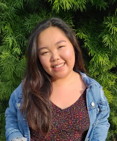 Elizabeth Nguyen, LMFT smiling with a green, luscious bush behind her