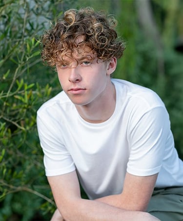 a young man sitting on a bench in a park