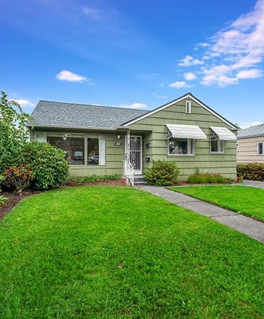a house with a green lawn and a small house