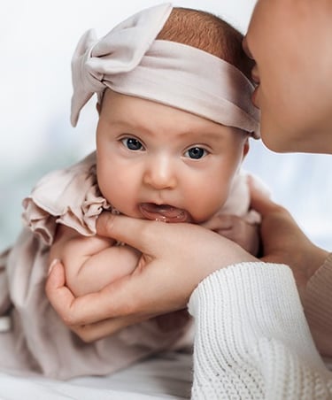 a baby girl in a pink dress and a woman in a white dress
