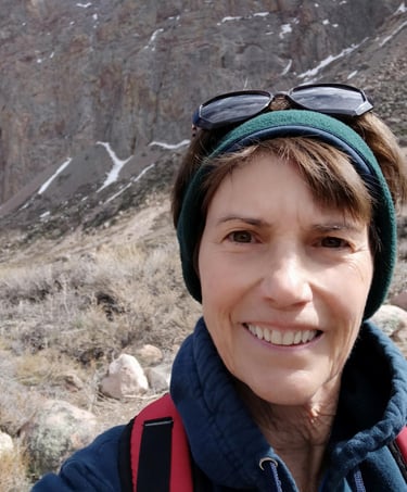 Susan Rensberger in the rugged Andes mountains wearing a headband and sunglasses on her head
