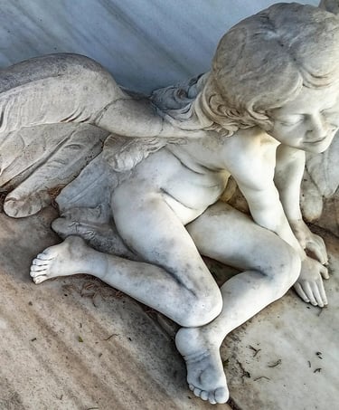 A detailed white marble cherub statue with feathered wings resting on a marble surface.