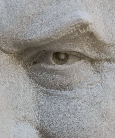 Extreme close-up of the eye of a relief of a man carved in white Macael marble.
