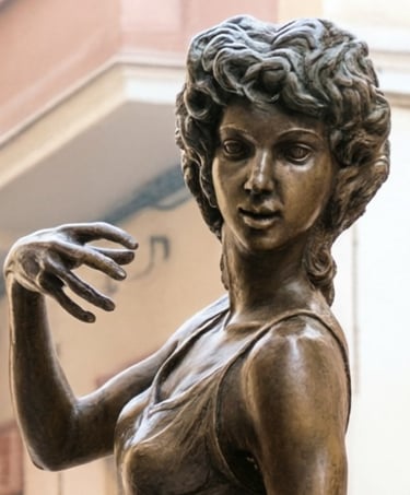 Bronze statue of a female dancer with curly hair and hand raised in a graceful pose.