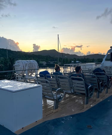 Ferry sailing at sunrise with warm golden light over calm waters in French Polynesia.