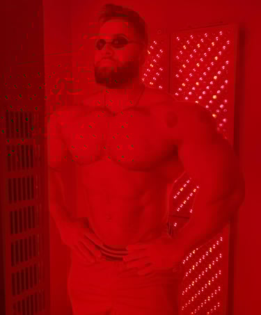 A muscular man uses a red light therapy panel for muscle recovery and skin health.