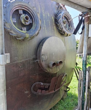 Creative face sculpture made from recycled metal parts and tractor tires on a rusty tank.