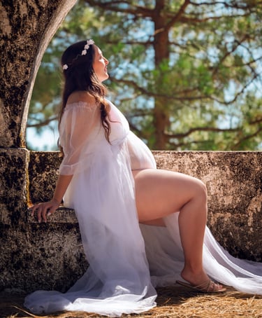 a woman in a white dress sitting on a stone wall