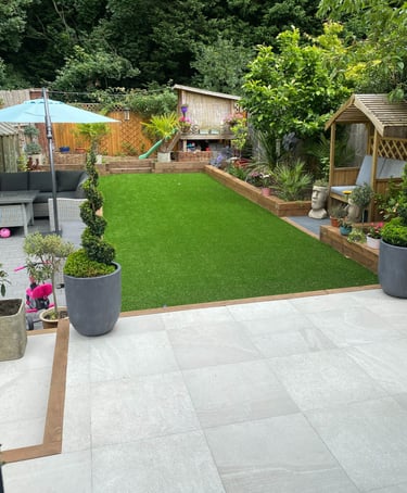 A family garden. The grass is green and there are lots of trees surrounding the lawn.