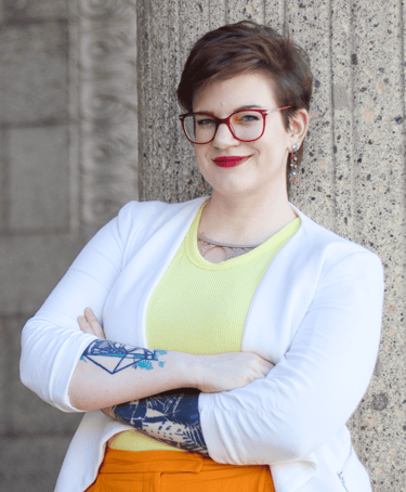 a photo of Swana Schuchmann with short hair, a white blazer and glasses, smiling