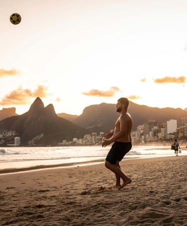 a group of people playing soccer on a beach