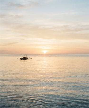 A serene coastal horizon at sunrise, soft golden light reflecting on calm ocean water, minimal composition, 35mm film