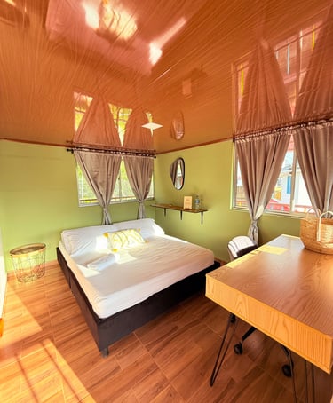 Habitación con cama doble, escritorio y grandes ventanas