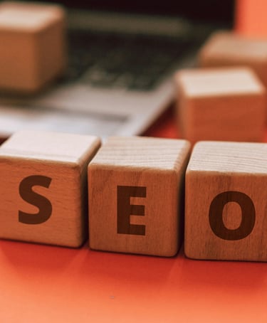 Wooden blocks spelling out SEO in front of blurred out laptop