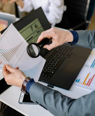 Business man looking at performance reports with a magnifying glass