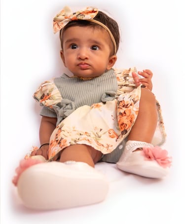 a baby girl sitting on a white surface