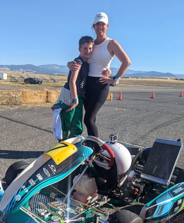 a woman and a boy are standing next to a race car