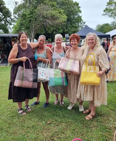 a group of women standing in a field with bags