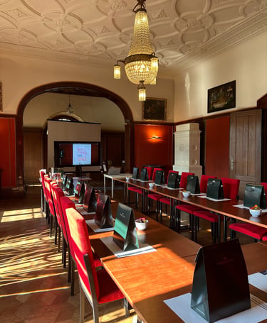 Elegant conference room with red chairs, crystal chandelier, and gift bags for a luxury corporate event.