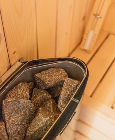Close-up of volcanic sauna stones in an electric heater inside a wooden Finnish sauna.